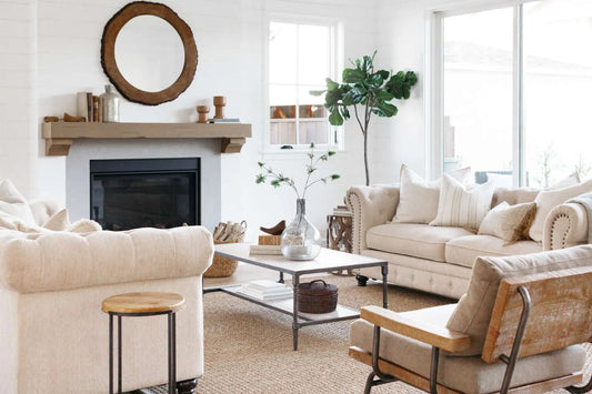 Living room with tan furniture surrounding fireplace and statement plant in corner