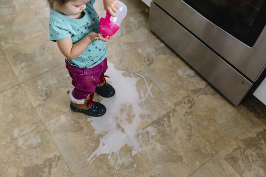 Young girl with spilled milk in kitchen