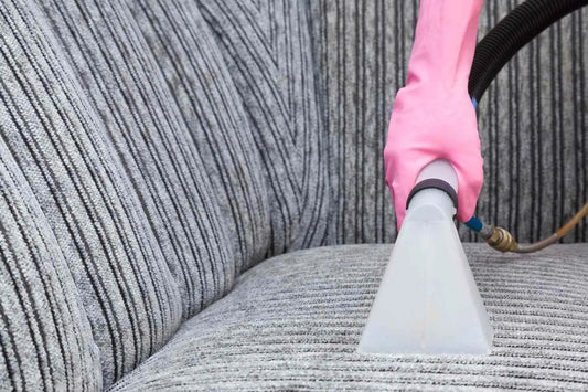 Dry cleaner's employee hand cleaning a modern sofa with professionally extraction method. Textile upholstered furniture. Early spring regular cleanup. Commercial cleaning company. Service concept.